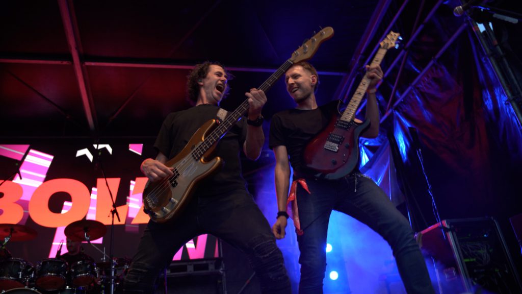 Twee gitaristen van Bold spelen samen op het podium